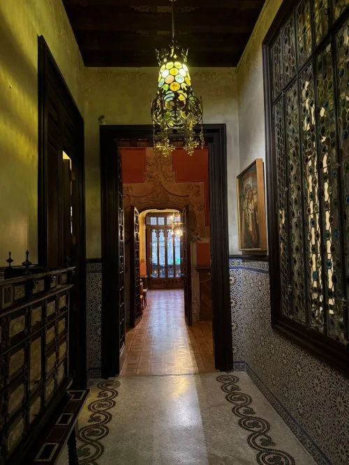 Pasillo distribuidor con ricas vidrieras, dinteles, lámparas con detalles cuidados de orfebrería, maderas nobles en las puertas