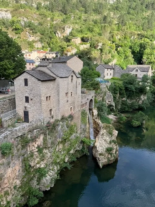 Saint- Cherly-du tarn con las casas que se elevan sobre un acantilado rocoso y el salto de agua
